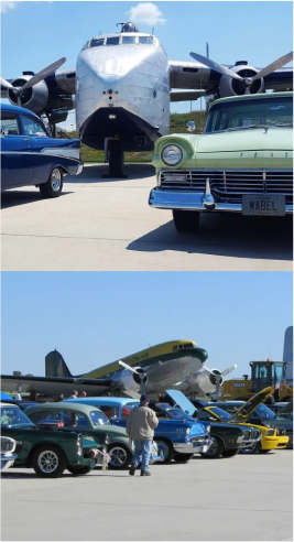 two classic cars parked in front of a Fairchild C-82 airplane